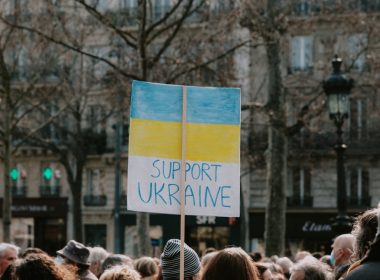 a crowd of people standing around a building with a sign that says support ukraine