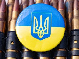 a blue and yellow button sitting on top of a bunch of bullet shells