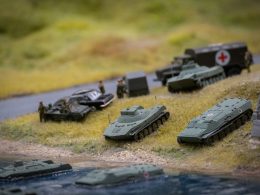 a group of military vehicles sitting on top of a grass covered field