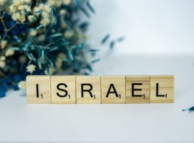a wooden block spelling israel next to a bouquet of flowers
