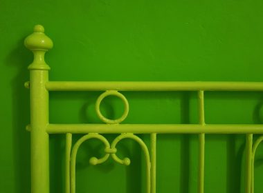 a green metal bed frame against a green wall