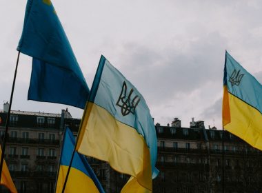 a group of flags with a building in the background