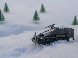 a toy tank in the snow with trees in the background