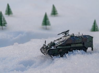a toy tank in the snow with trees in the background