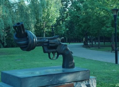 A statue of a gun is in the middle of a park