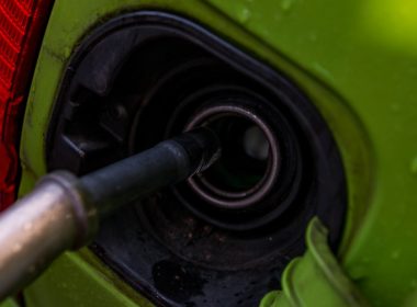 A close up of a green car with a gas nozzle