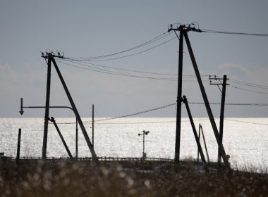 Power lines silhouetted against a sparkling sea.