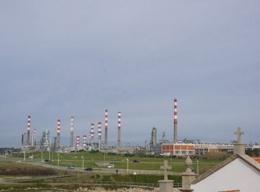 Oil refinery chimneys stand under a cloudy sky.