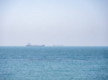 Two large cargo ships sail on a calm blue ocean.